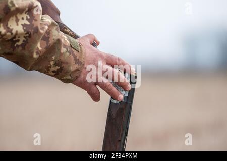 Close up shot of an unloaded gun handled by am adult man during a shooting day. Man is loading the gun Stock Photo