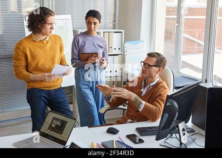High angle portrait of team leader giving instructions to colleagues while collaborating on project in IT development studio, copy space Stock Photo