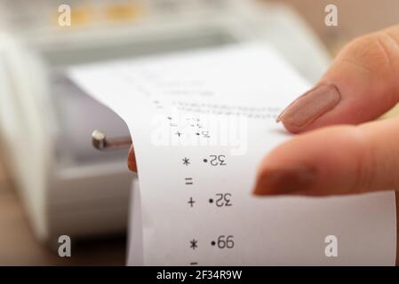 Closeup of a paper receipt printout coming out of an adding machine. Stock Photo