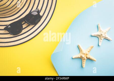 composition of sunglasses, exotic seashells and starfish on blue and yellow background, top view. Summer sea flat lay Stock Photo