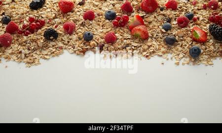 From above bunch of assorted fresh berries placed on pile of natural muesli for breakfast on gray background Stock Photo