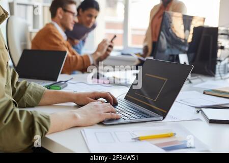 Side view closeup of IT programmer writing code on laptop screen while working in software production studio with focus on male hands typing at keyboa Stock Photo