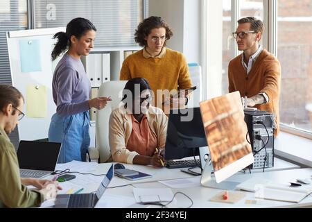 Portrait of diverse IT development team using computer together while working in software production studio Stock Photo