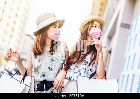 young woman wearing face protective medical mask and holding shopping bags on the street Stock Photo