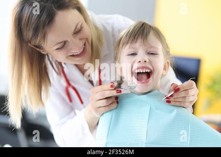 Dentist examines teeth of smiling girl closeup Stock Photo