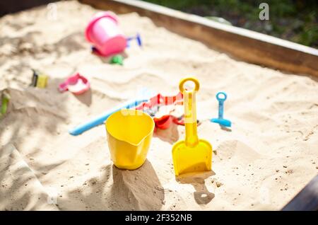 Sandbox outdoor. Children's wooden sandbox with various toys for the game. Summer concept. Selective focus with shallow depth of field Stock Photo