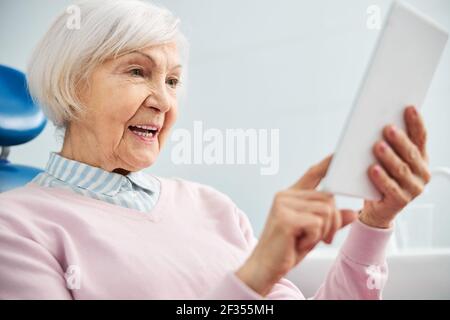 Confused aging female pressing on tablet display Stock Photo