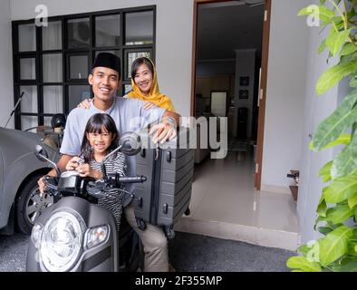 asian muslim family riding motorbike scooter together traveling with kid Stock Photo