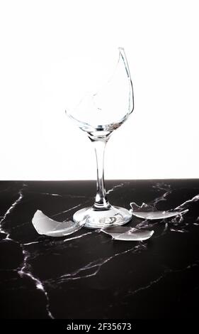 Broken shattered wine glass and shards on marble table Stock Photo