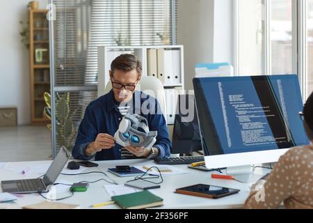 Portrait of male software engineer holding VR headset while working on augmenter reality applications, copy space Stock Photo