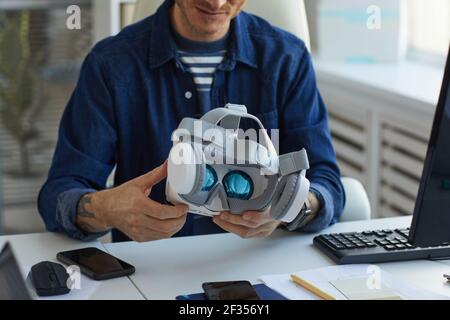 Cropped portrait of unrecognizable IT developer holding VR headset while working on augmenter reality applications, copy space Stock Photo