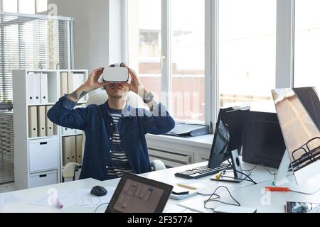 Portrait of modern IT developer wearing VR headset while working on augmenter reality games and software, copy space Stock Photo