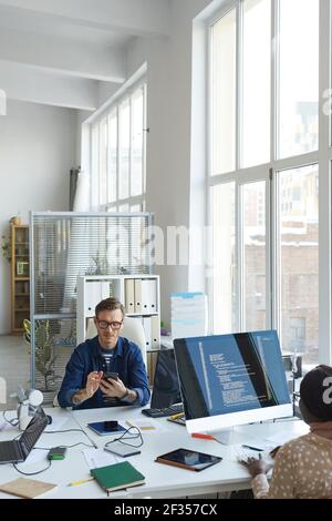 Vertical portrait of modern IT developers using computers for code programming while working on VR software in office, copy space Stock Photo