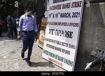 Mumbai, India. 15th Mar, 2021. A bank employee walks past a sign protesting against the proposed privatization of two public sector banks in Mumbai, India, March 15, 2021. Banking services across India were hit Monday in the wake of a countrywide two-day strike against the proposed privatization of two public sector banks and retrograde banking reforms, officials said. According to United Forum of Bank Union (UFBU), an umbrella body of nine bank unions in India, over a million bank employees and officers participate in the strike. Credit: Fariha Farooqui/Xinhua/Alamy Live News Stock Photo