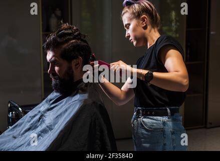 shot of hairdresser cutting hair of handsome man client, Hairstylist serving client at barber shop Stock Photo