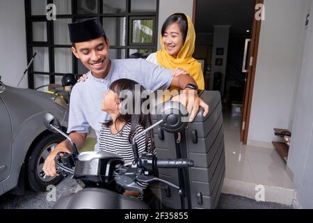 asian muslim family riding motorbike scooter together traveling with kid Stock Photo