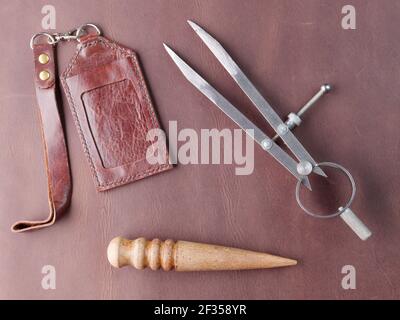tools for working with leather lie on a brown leather background, the concept of a tanner, master of working with leather Stock Photo