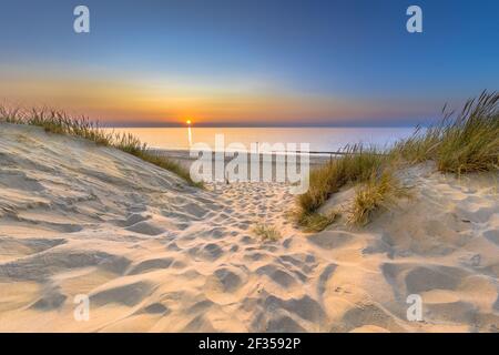 Inviting Sunset View over ocean from dune over North Sea and Canal in Ouddorp, Zeeland Province, the Netherlands. Outdoor scene of coast in nature of Stock Photo