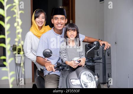 asian muslim family riding motorbike scooter together traveling with kid Stock Photo