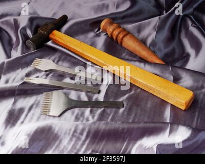 Craftsmen for leather and hammer lie on silk fabric, craft concept Stock Photo