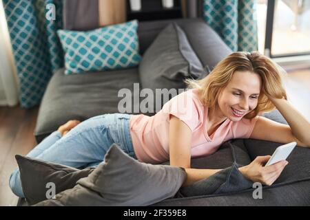 Cheerful woman using modern smartphone at home Stock Photo