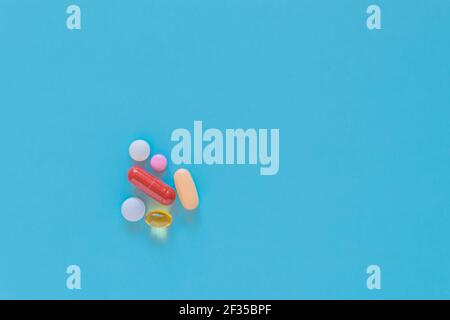 Multicolor tablets, pills, and capsules on blue background. Colorful medication on turquoise surface with copy space. Top view of drugs. Stock Photo