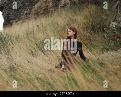 Woman sits on dry grass in nature in the forest in autumn Stock Photo
