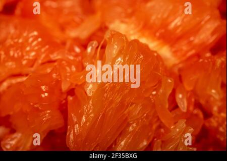 Red honey pomelo peeled and disassembled into slices. Close-up selective focus. Stock Photo