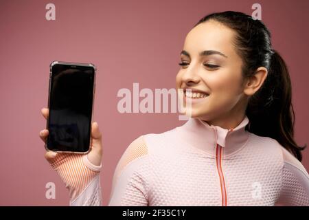 Cheerful young woman holding cellphone with black display Stock Photo