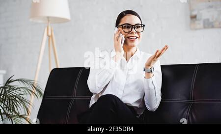 excited businesswoman talking on mobile phone and pointing with hand in office Stock Photo