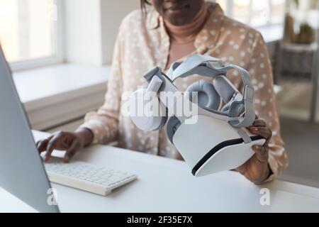 Cropped portrait of female IT developer holding VR headset while working on augmented reality games and software, copy space Stock Photo