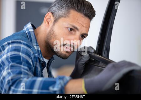 male mechanic fitting rubber onto car door Stock Photo