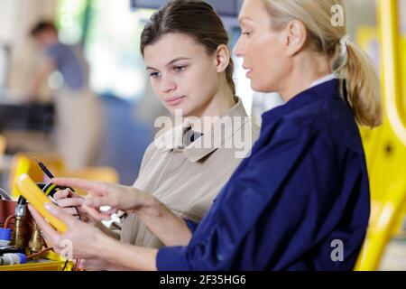 female electrician and apprentice working on checking status equipment Stock Photo