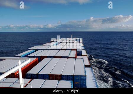 Container vessel sailing over the Pacific ocean in winter, the containers are covered with a thin layer of snow. View from the navigation bridge. Stock Photo