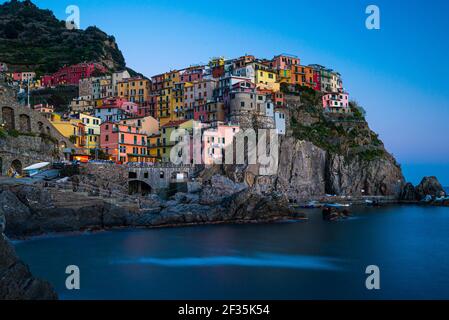 Close-up of various color painted houses on high cliff above sea. Manarola old fishing village at dusk. Cinque Terre, Liguria, Italy. Stock Photo