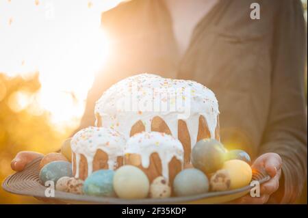 Girl holding a wooden plate with easter cake and eggs Stock Photo