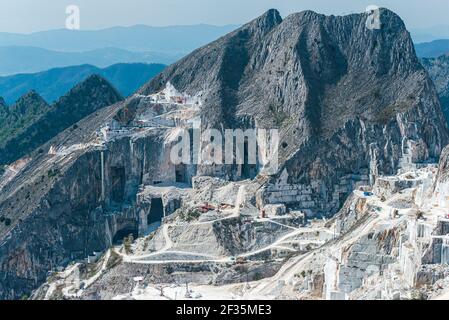 Panoramic view of Carrara marble quarry. Mining site with several holes into mountain. Construction and mining raw material concept. Stock Photo