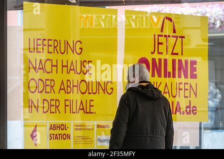 Regensburg, Germany. 15th Mar, 2021. A man stands in the city centre in front of a sign saying 'Delivery to home or pick up at branch', which is attached to a shop window of a department store. In Regensburg, Landshut and several other larger cities, the 'emergency brake' is now in effect with tightened restrictions again because the incidence of more than 100 new infections per 10,000 inhabitants was exceeded on three consecutive days. Credit: Armin Weigel/dpa/Alamy Live News Stock Photo