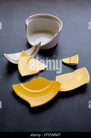 Broken white and yellow pottery scattered on kitchen countertop Stock Photo