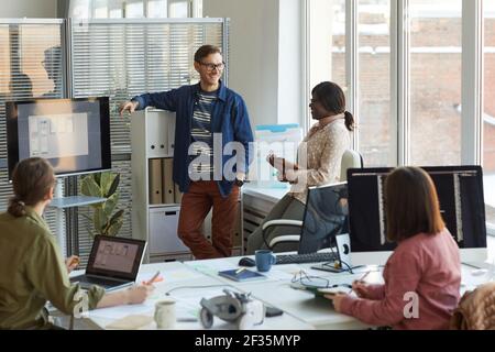 Wide angle view at multi-ethnic IT developers team discussing project during meeting in office, copy space Stock Photo