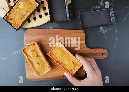 Man's Hand Holding a Square Shaped Fresh Baked Pumpkin Cake Bar Placing on the Wooden Breadboard Stock Photo