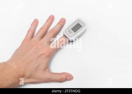 The guy's hand measures saturation with a modern medical device pulse oximeter on a white background. Stock Photo