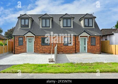 Front of new semi detached housing & home just completed house building paved over front garden car parking in existing suburban street Brentwood UK Stock Photo