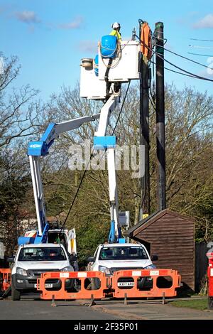 UK Power Networks distribution business cherry picker truck & electrician workers connecting new electricity supply cable at top of pole  Essex UK Stock Photo