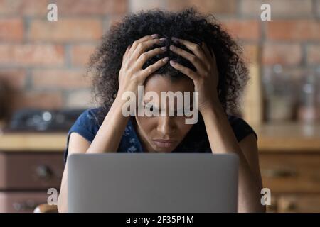 Nervous young african female scratch head stare at laptop screen Stock Photo