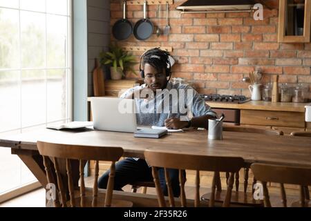 Young black guy learning from home using laptop and headset Stock Photo