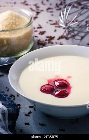 Semolina porridge with cherries and chocolate sprinkles and cane sugar in the back Stock Photo