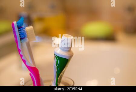 red toothbrush, green toothpaste and white sink 2021 Stock Photo