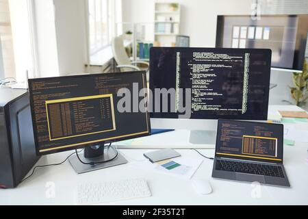 Background image of several computer screens with code lines on desk in IT developers office, copy space Stock Photo