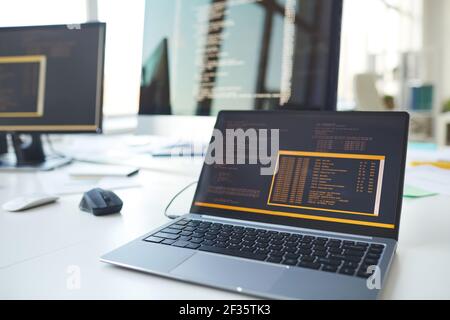 Background image of open laptop with code on screen at desk in IT developers office, copy space Stock Photo